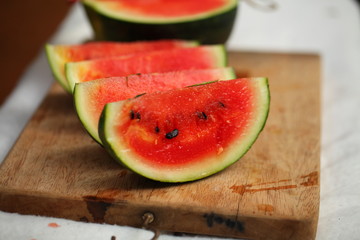 cutting fresh ripe watermelon into pieces with a knife on a wooden table