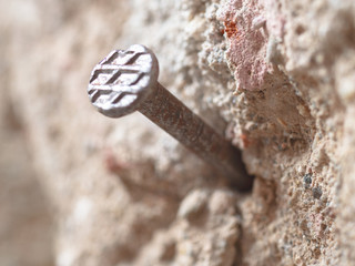 close-up of rusty nail in old stone and concrete wall