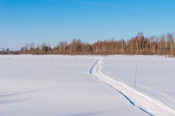 Fototapeta na wymiar Winding snowmobile road on a snowy field