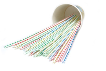 cocktail colored straws in a paper glass for drinks on a white isolated background