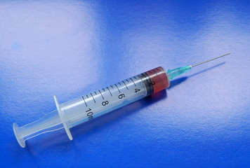 Syringe with medicine, needle, close-up on a blue background