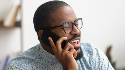 Excited African American businessman talking on phone at workplace