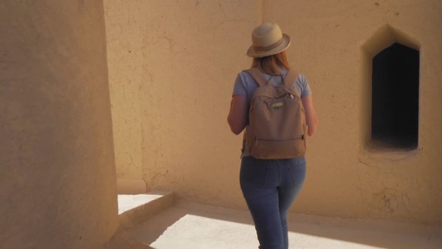 Young Foreign Female Tourist Visiting Ancient Bahla Fort in Oman. Woman in Active Solo Travel in Middle East Countries