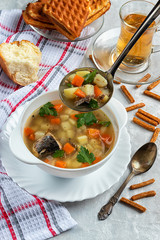 Fish soup with potatoes and carrots, on a concrete background with greens and crackers and a ladle