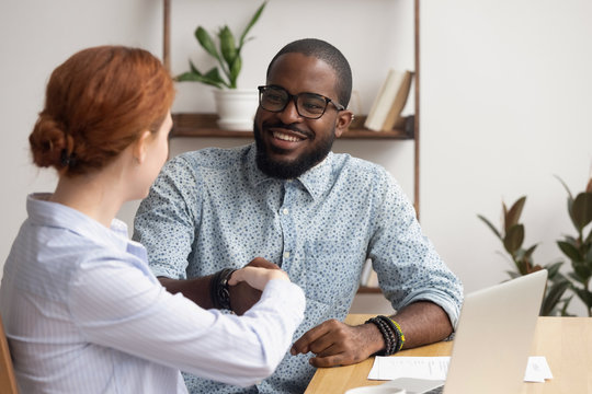 Businesswoman shaking hand of African American colleague at workplace