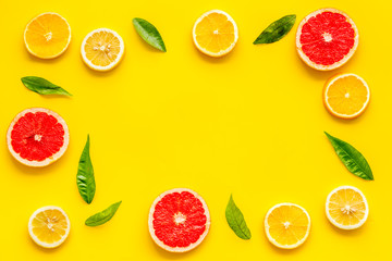Citrus fruits - lemons, grapefruit slices - on yellow background mockup, frame top-down copy space