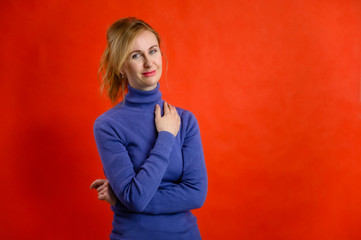Portrait on a red background pretty woman blonde Caucasian 40 years old stands right in front of the camera