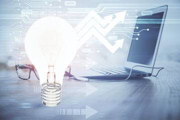 Computer on desktop in office with bulb icon hologram. Multi exposure. Concept of idea.