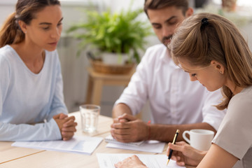 Serious businesswoman signing contract at meeting with business partner