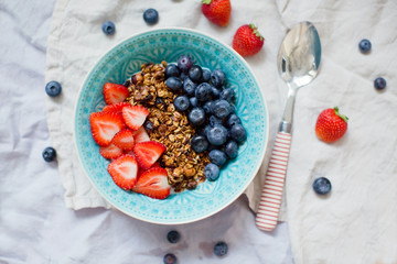 Bowl of homemade granola with yogurt and fresh strawberry and blueberry
