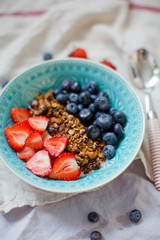 Bowl of homemade granola with yogurt and fresh strawberry and blueberry