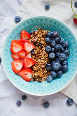 Bowl of homemade granola with yogurt and fresh strawberry and blueberry