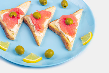 Appetizer, open sandwich with salmon on a blue plate on white background. Traditional Italian or Scandinavian cuisine. Concept of proper nutrition and healthy eating. Close up, copy space for text