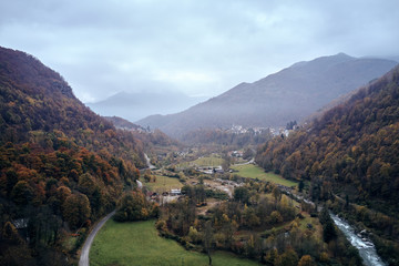 Alpine valley with mountain river and village cantoira with a lot of green  grass in a foggy autumn day 