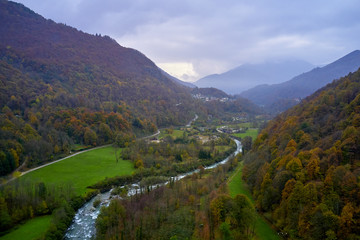 Alpine valley with mountain river and village cantoira with a lot of green  grass in a foggy autumn day 