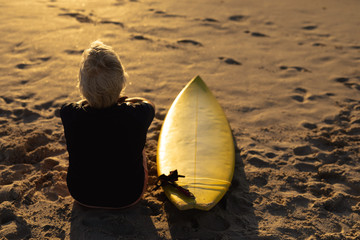 Old woman with a surfboard at the beach