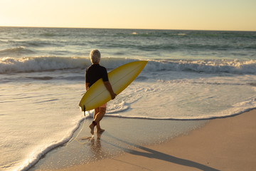 Old woman with a surfboard at the beach