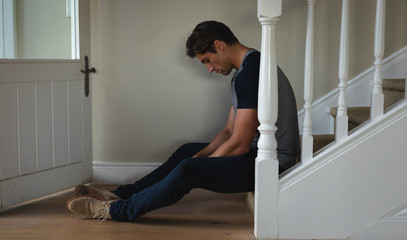 Worried man sitting in the stairs at home