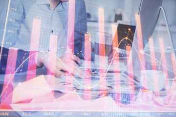 Multi exposure of chart with man typing on computer in office on background. Concept of hard work.