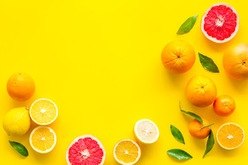 Fresh citrus frame. Oranges, tangerines, grapefruits, leaves on yellow background top-down copy space