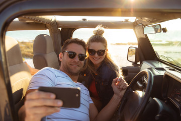 Couple taking selfies in a car at the beach