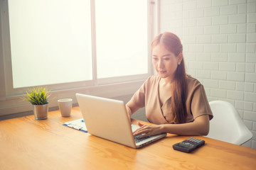 Asian young businesswoman working with new project laptop drinking coffee in coffee shop cafe, Analyze plans, papers, hands writing business plan.design notebook technology  startup business concept