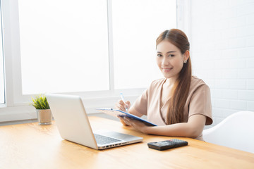 Asian young businesswoman working with new project laptop drinking coffee in coffee shop cafe, Analyze plans, papers, hands writing business plan.design notebook technology  startup business concept