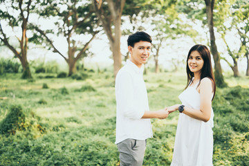 Portrait of Happy young Asian couple in love having a good time and embracing in the park, woman hugs her boyfriend after receiving gift on valentine day, Good Healthy relaxation enjoy vacation summer