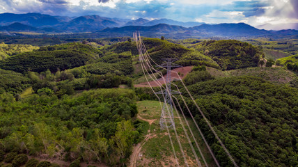 electric pole high voltage towers with green tree forrest ,aerial drone view