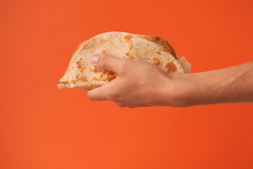 Mexican national food taco or Tatar national food kystyby in hand on an orange background.Food in a tortilla.National food concept