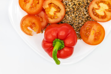 A clean white plate contains fresh vegetables and buckwheat