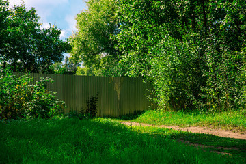 Metal fence in the countryside among green grass and blue sky