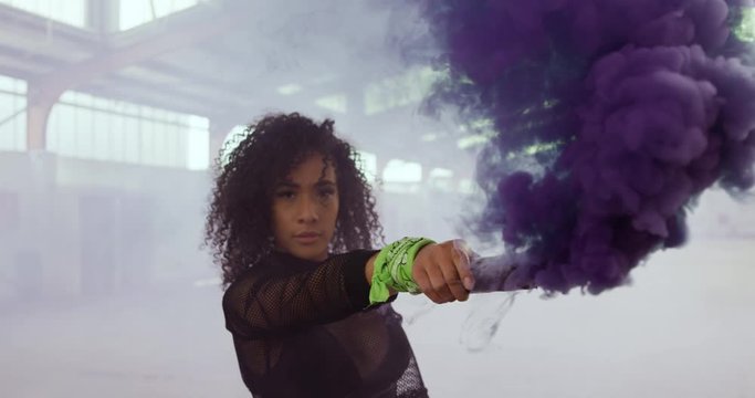 Female dancer in an empty warehouse holding smoke grenade