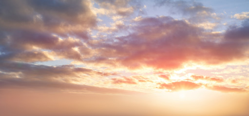 Dramatic sunset background of orange and yellow clouds against a blue sky background.