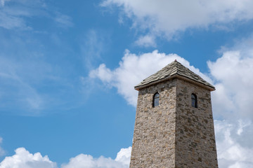 Fototapeta na wymiar Ancient stone tower on a blue cloudy sky background.