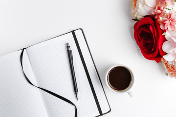 Black closed Notepad with a pen with a Cup of coffee with a flower top view on a white background. Space for text