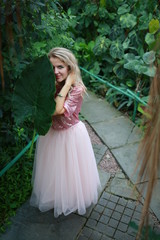 Fototapeta premium beautiful girl in a tropical garden with a huge green leaf