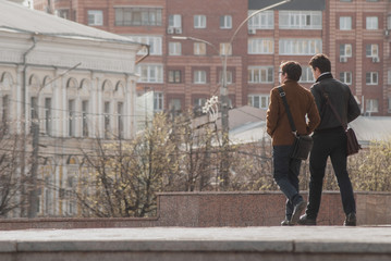 Two young men are returning from work, men are walking in the background of the city,