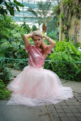  beautiful white long hair girl in a tropical garden in a light tulle pink skirt