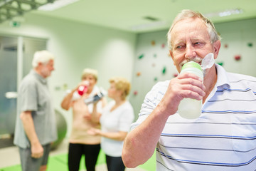Senior trinkt aus einer Wasserflasche im Kletterkurs
