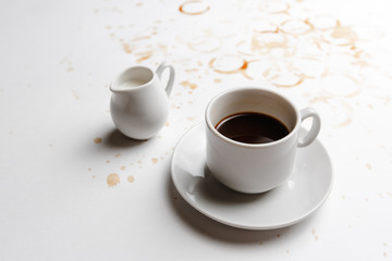 a Cup of black coffee with a decanter for cream on a coffee-filled white background top view. a place for a label