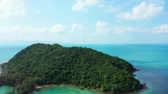 Isolated tropical island with trees forest and rocky shoreline in the middle of colorful lagoon with clear turquoise water and coral reefs, ko tae nai, Thailand