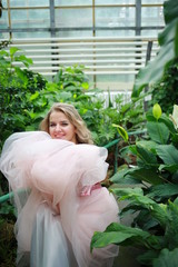  beautiful white long hair girl in a tropical garden in a light tulle pink skirt