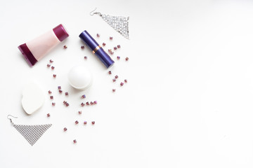 Flatlay, beauty, creams, lipstick, earrings, sponge and beads on a white background