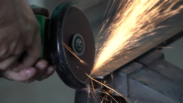 Worker with Angle Grinder does Metalworking in Industrial Environment.