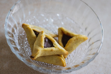 Hamantaschen. (ozeney haman) Triangular pastry of crispy dough, stuffed with poppy or halva or chocolate. For the Jewish holiday Purim. Home baking, in a crystal bowl. Handmade