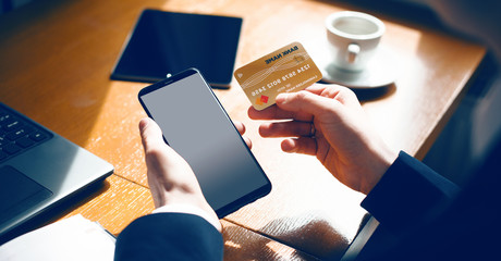Caucasian entrepreneur holding a mobile with blank space and a bank card for buying something