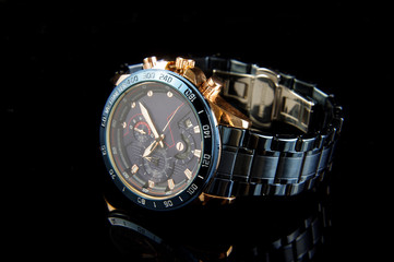 Professional luxury golden blue male watch on the black reflective surface