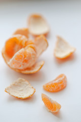 ripe orange mandarin with slices and peel on a white table.