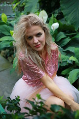  beautiful white long hair girl in a tropical garden in a light tulle pink skirt